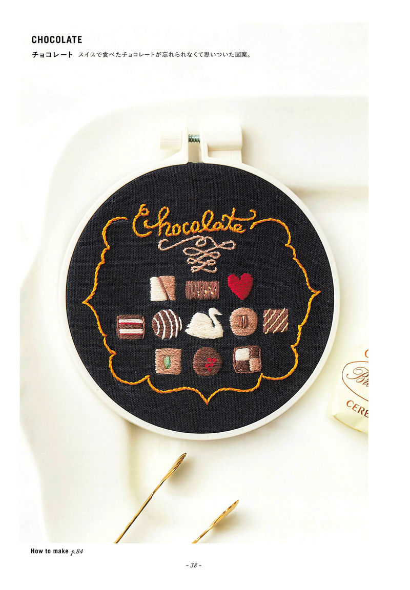 20221014_670 Chocolate embroidery pattern on black fabric with assorted truffles, a swan, a heart and script lettering
