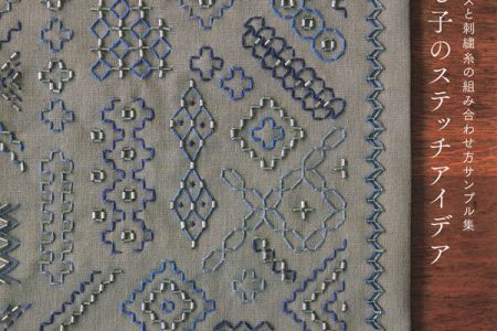 Cover of this Japanese beads sashiko embroidery book showing dense blue and silver geometric sashiko bead stitch patterns on grey linen fabric.