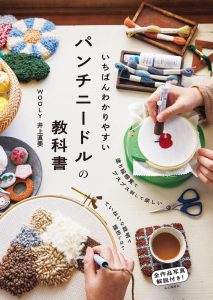 Cover of this Japanese punch needle embroidery guide showing hands working on a hoop with thick thread alongside completed loop-textured projects and craft tools.