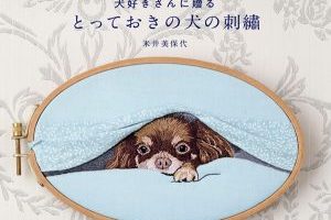 Cover of a Japanese dog embroidery patterns book showing a realistic silk shading embroidery of a Chihuahua peeking from under a blanket displayed in an oval wooden hoop.