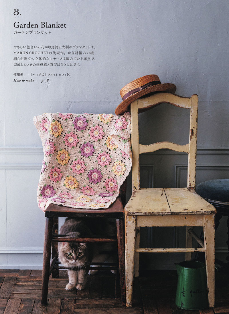 00016 Garden Blanket draped over a chair — a crochet flower square blanket in soft pink, lilac and yellow