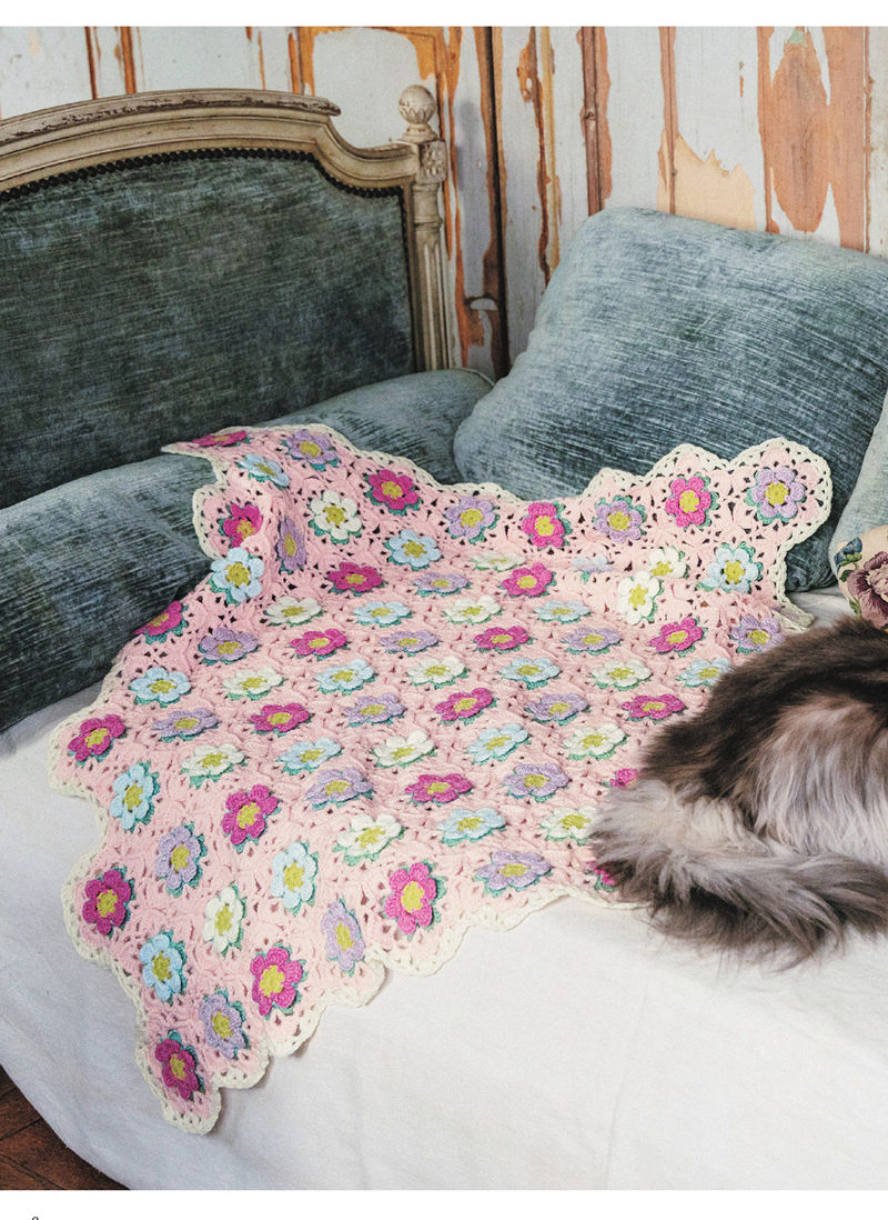 00020 Bright crochet daisy blanket pattern in pink, lilac and blue flowers spread over a velvet daybed