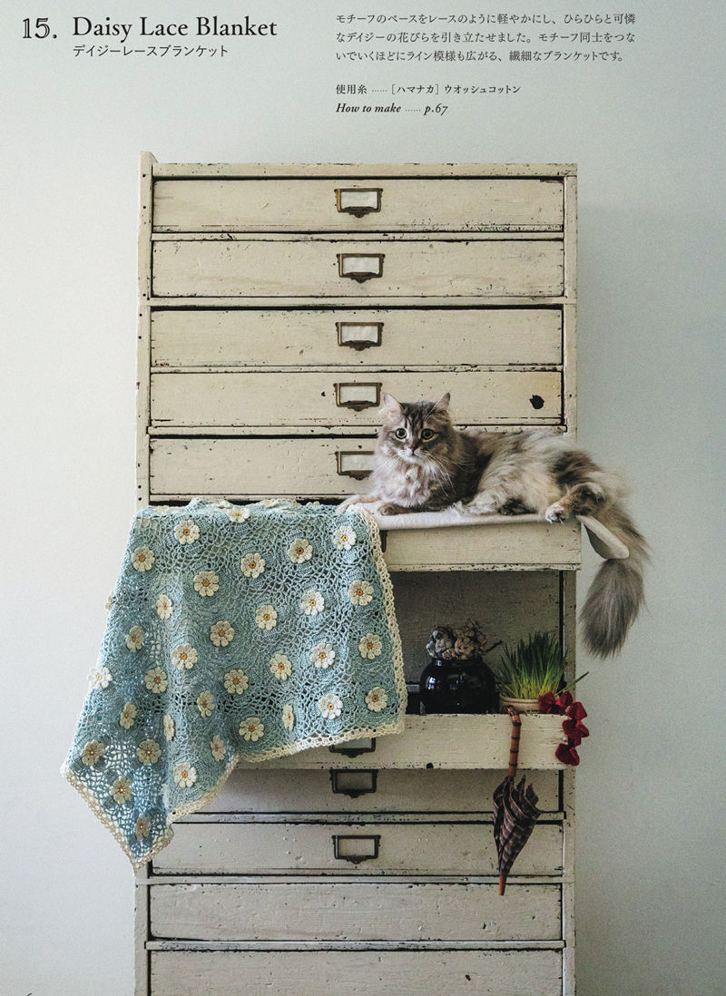 00028 Crochet lace blanket pattern in sage blue with cream daisies, draped over an antique plan chest