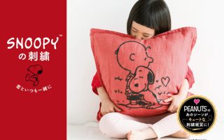 Snoopy embroidery patterns book cover showing a child hugging a large red cushion embroidered with Charlie Brown and Snoopy