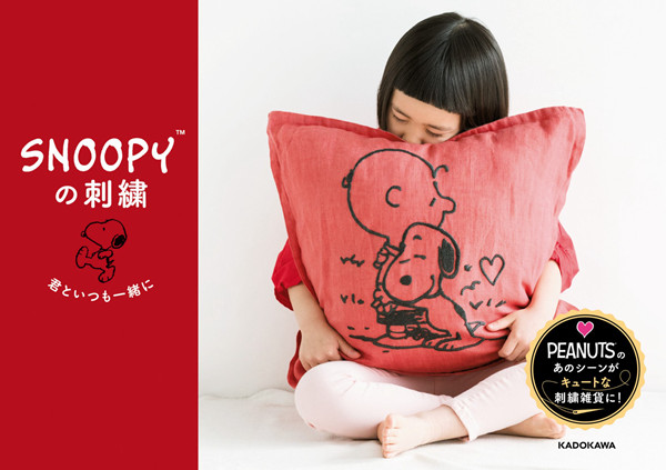 Snoopy Embroidery Patterns — 30+ Irresistible Seasonal Projects for Every Peanuts Fan Cover - Kayliebooks Snoopy embroidery patterns book cover showing a child hugging a large red cushion embroidered with Charlie Brown and Snoopy