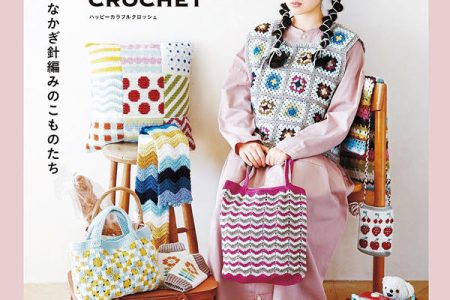 Cover of a Japanese colorful crochet patterns book showing a model wearing a granny square vest and holding zigzag bags surrounded by baskets, blankets and home accessories.