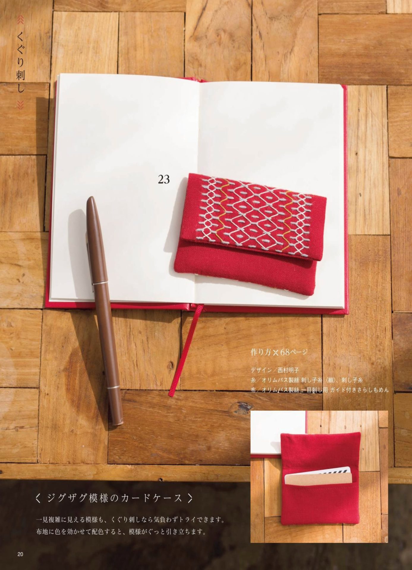1283-p22 Red sashiko card case with zigzag stitching resting on an open notebook with a fountain pen