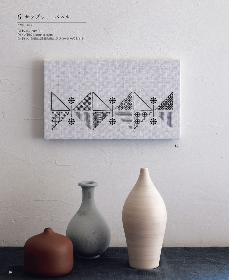 1489-00012 Framed linen panel with a triangle border pattern on a shelf among gray ceramic vases