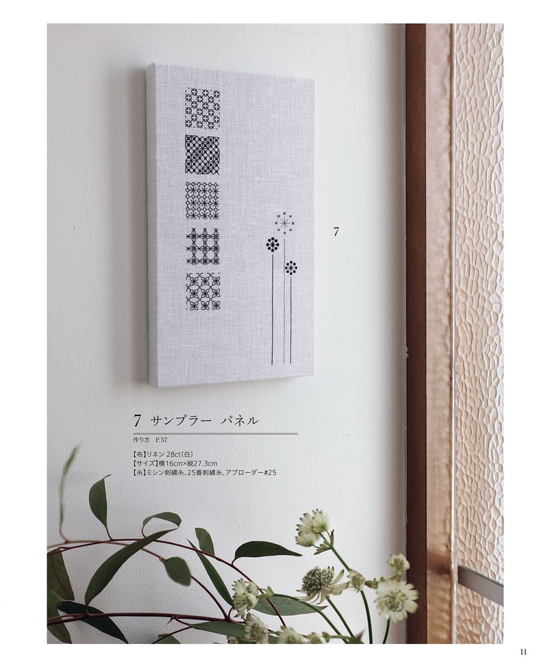 1489-00013 Tall wall panel stitched with stacked geometric samples and a flower motif beside a plant