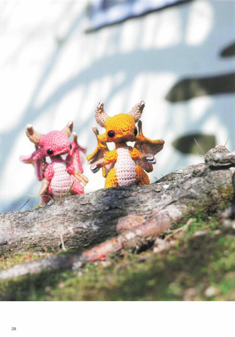 1495-04232026184535_031 Pink and yellow crochet dragons perched on driftwood against a bright sky