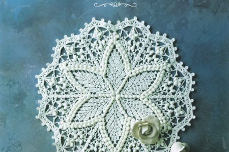 Cover of a book of crochet doily patterns A to Z, a white star doily with bobble stitches and roses on dusky blue