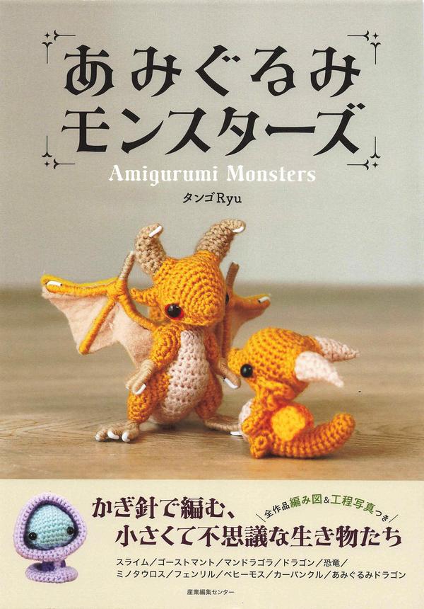 Amigurumi monsters crochet patterns cover with two small orange crochet dragons on a wooden table